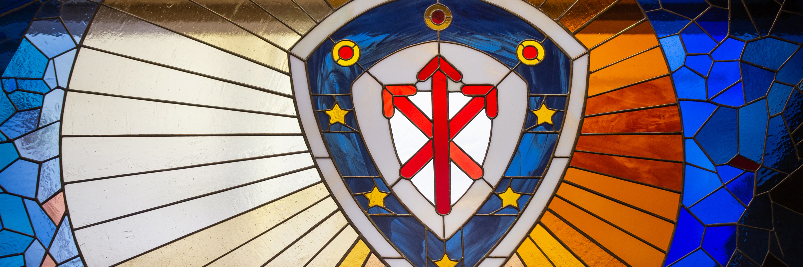 The College of Arts and Sciences crest in red, blue and yellow stained glass