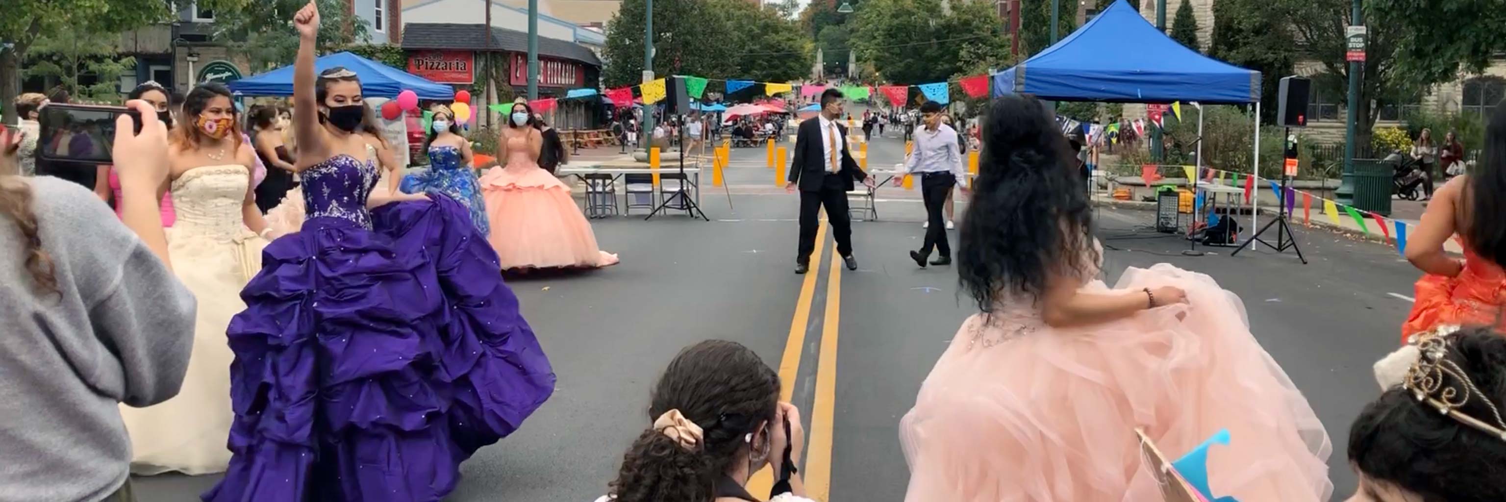 A street celebration with several young women in formal gowns.