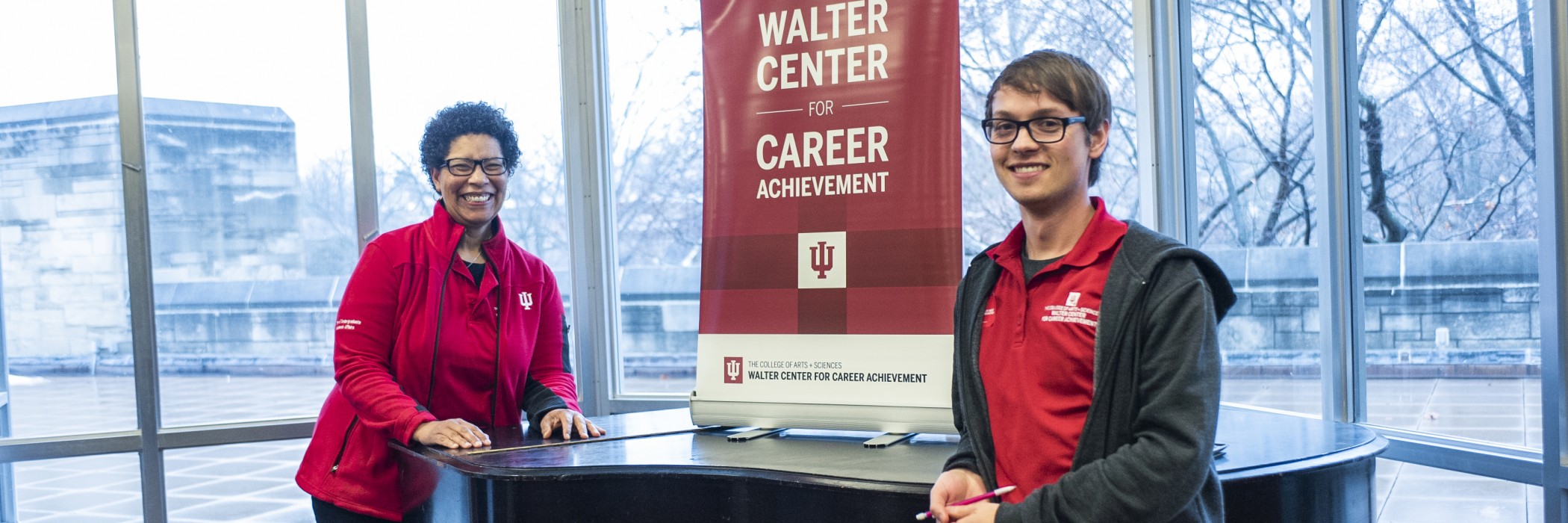 Two career coaches in red shirts in front of a sign that reads “Walter Center for Career Achievement”