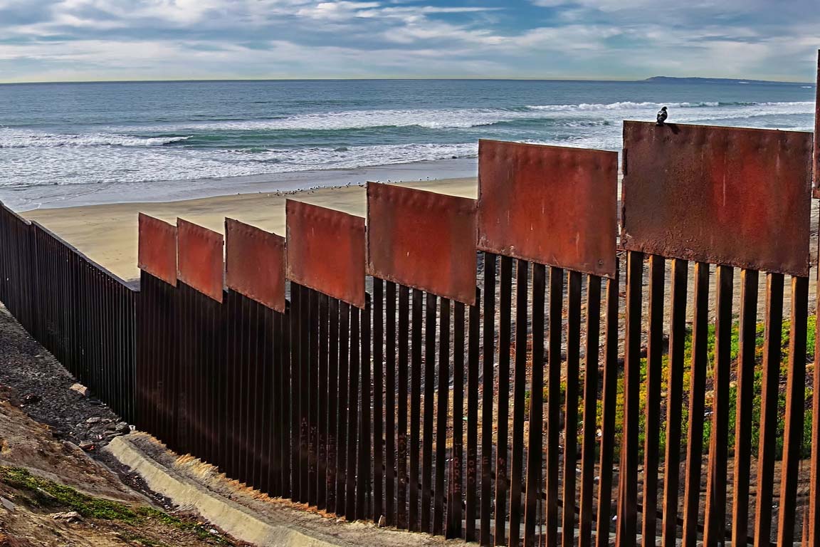 A view of a border fence separating the United States from Mexico.